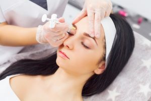 Close up of hands of cosmetologist making botox injection in female