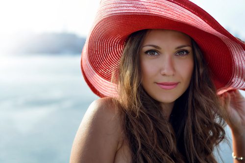 lady in a red hat smiling at the summer waterfront-img-blog