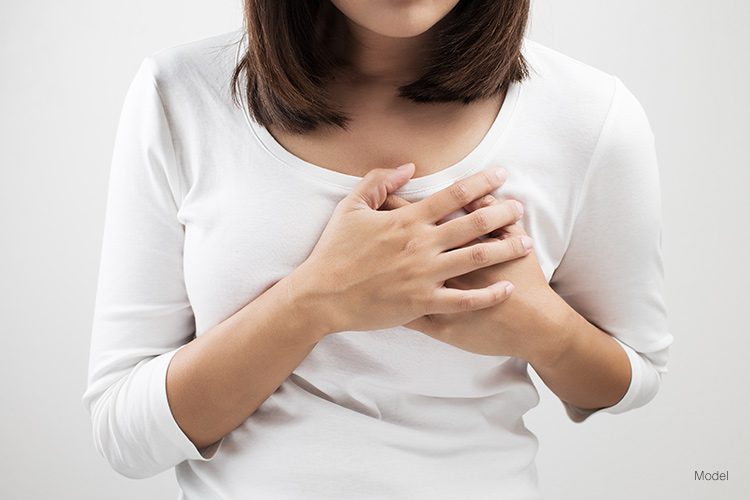 Women with her hands covering her breast over a light background.